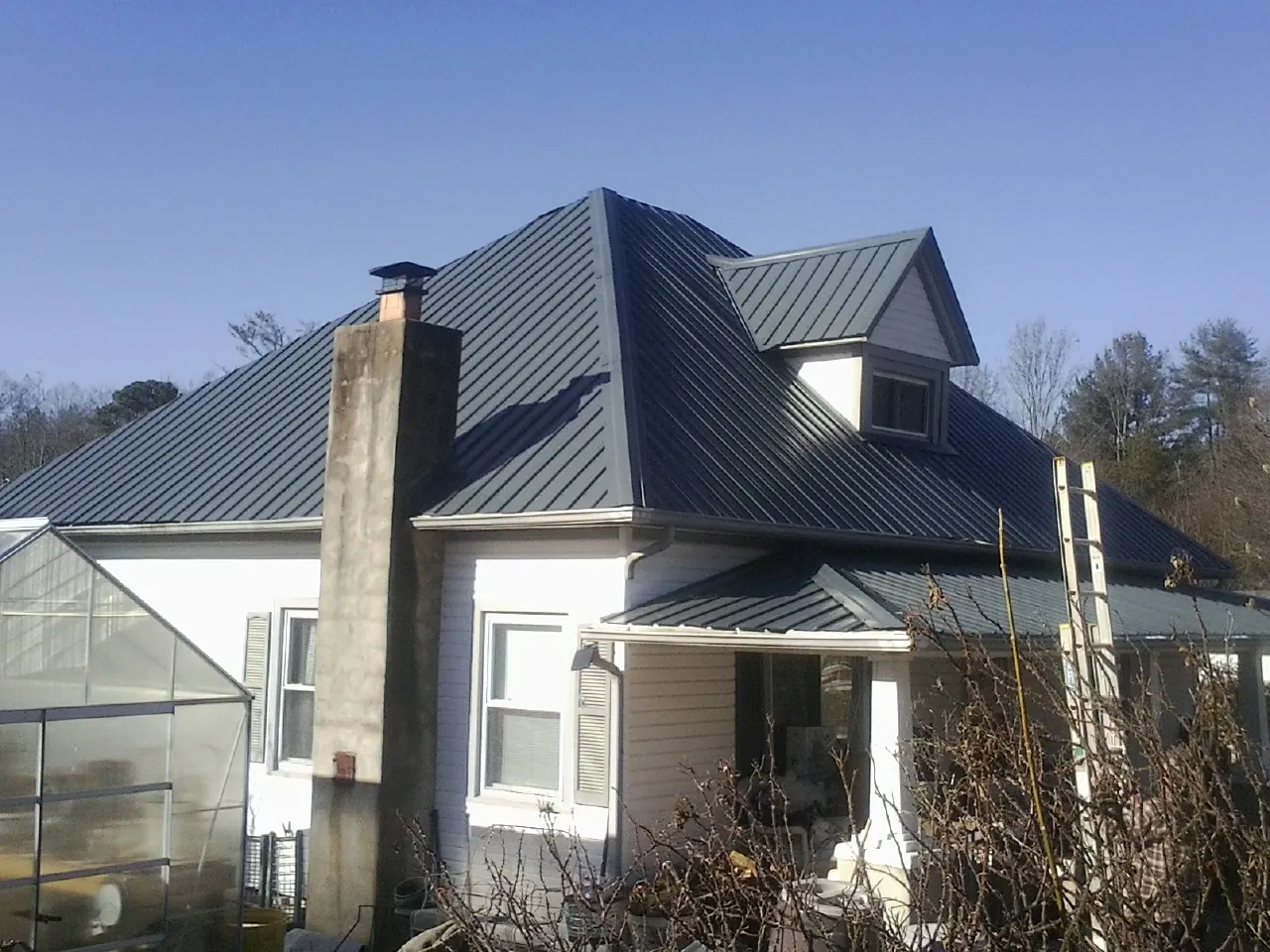 Dark blue standing seam metal roof on a white farmhouse with dormer — Slate & Tile Roof Repair by Roofing Brothers in Ridgeville