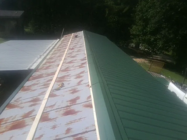 Old rusted panels beside newly installed green metal roofing — Wind Damage Roof Repair by Roofing Brothers in Ridgeville