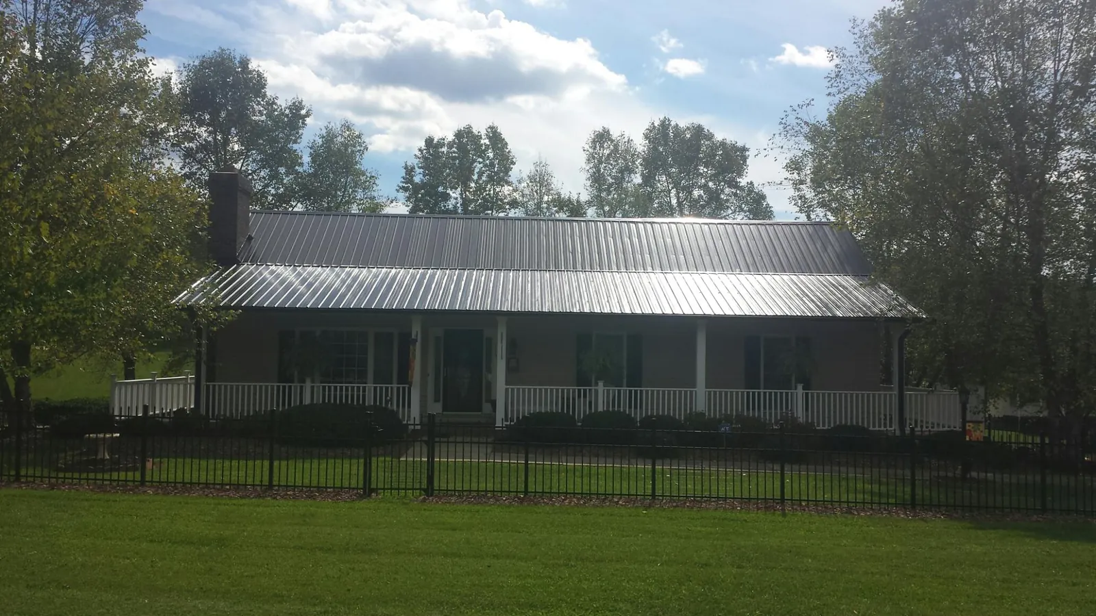 Gray metal roof on a brick ranch with a full width front porch — Gutter Guard Installation work by our crew in Ridgeville