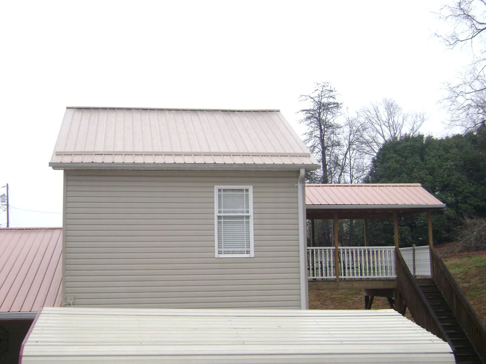 Tan metal roofs on a two story addition and attached porch, from a Roof Replacement job in Ridgeville