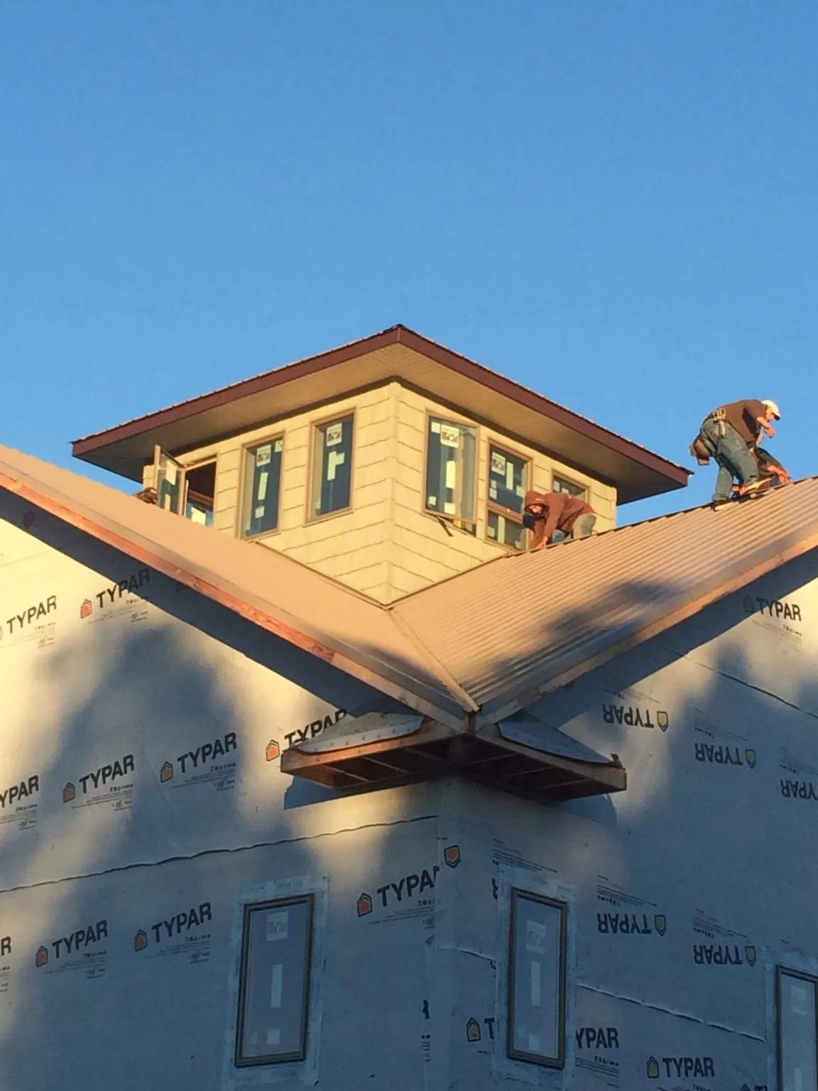 Roofers working around a rooftop cupola on a new metal roof at sunset — Roof Waterproofing in Ridgeville by Roofing Brothers